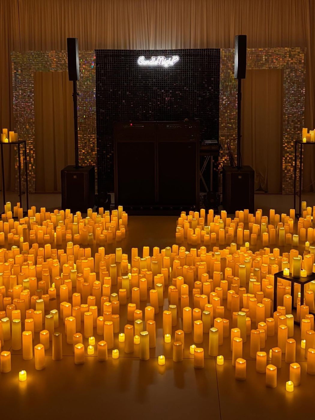 Insegna luminosa CandleNight tra un mare di candele