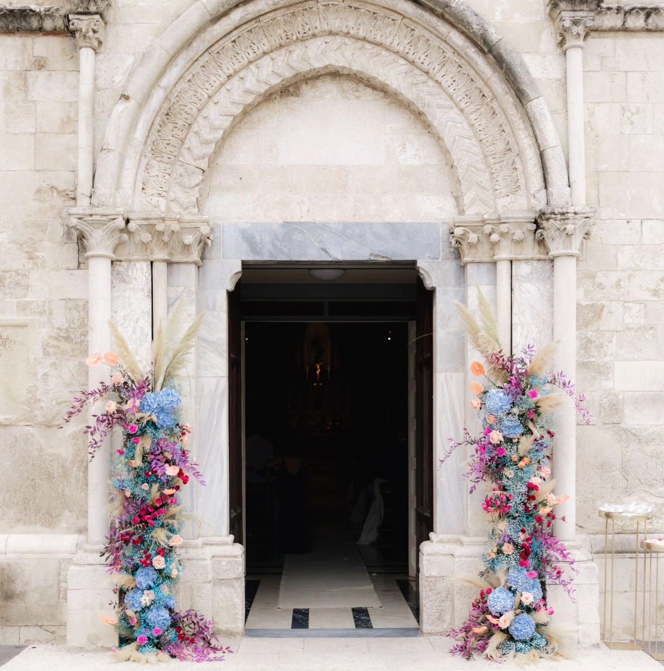 Portale di una chiesa incorniciato da composizioni floreali colorate